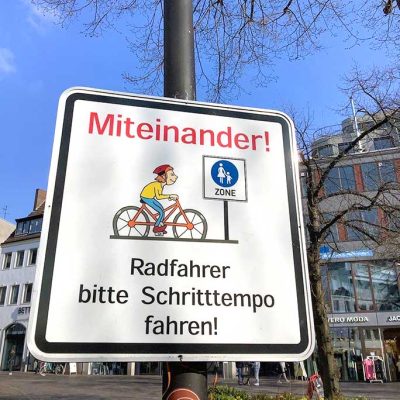 Verkehrsschild mit der Aufschrift „Miteinander! Radfahrer bitte Schritttempo fahren!“