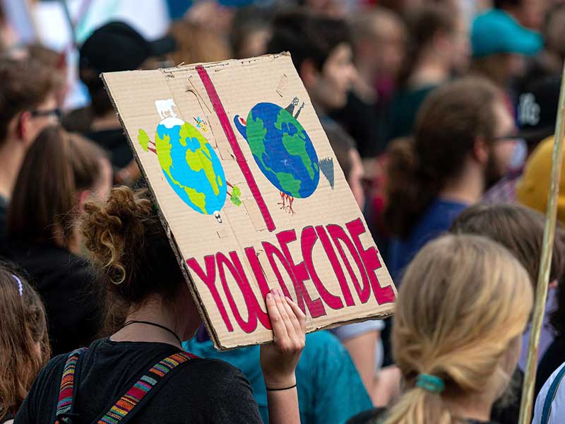Viele Menschen auf einer Klima-Demonstration. Eine Frau hält das Schild „You decide“ in die Höhe.