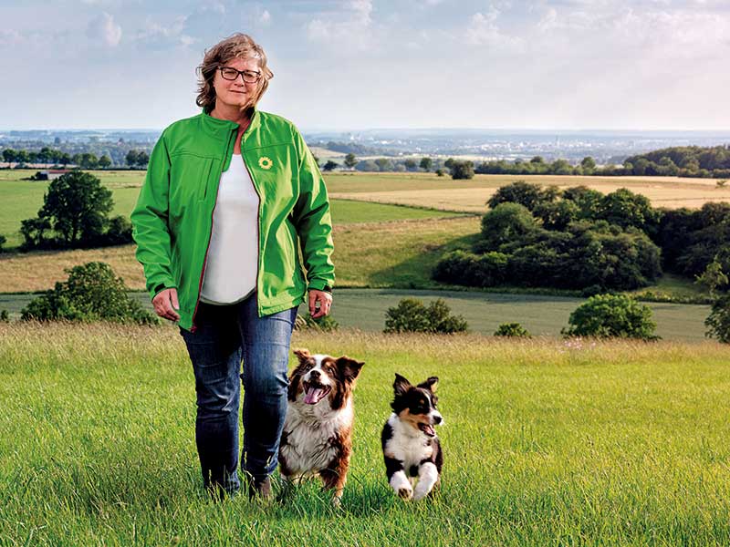 Norika Creuzmann MdL mit zwei Hunden auf einer Wiese.