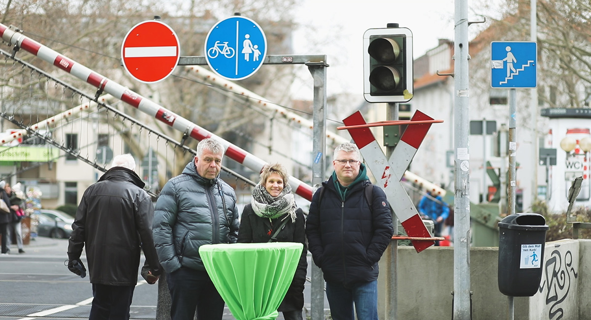 Menschen warten am Bahnübergang Rosentor