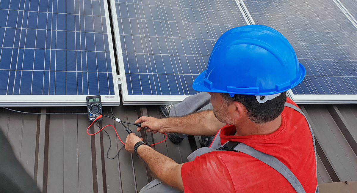 Ein Monteur installiert Photovoltaik-Panels auf einem Dach.