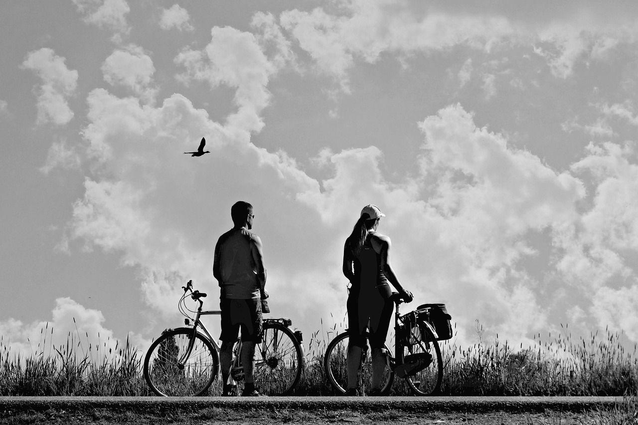 Zwei Radfahrer*innen vor wolkigem Himmel