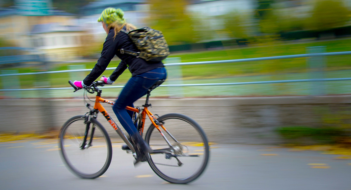 Eine junge Frau fährt auf einem Fahrrad eine Straße entlang.