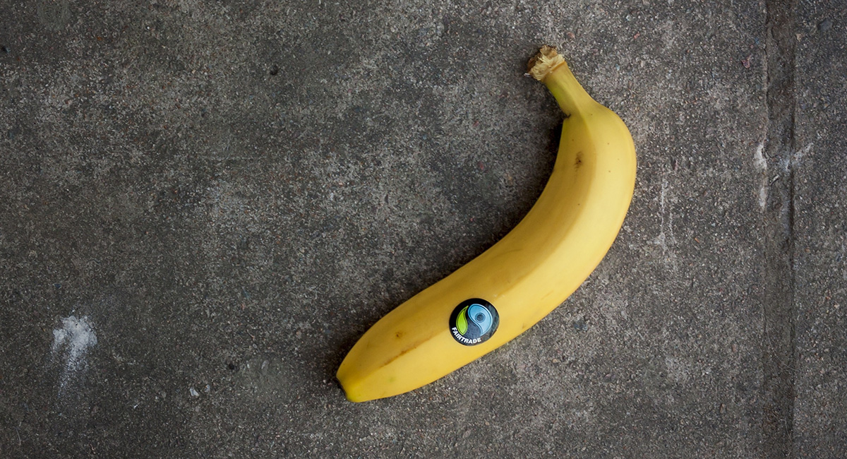 Eine Banane mit Fairtrade-Aufkleber liegt auf einer grauen Steinplatte.