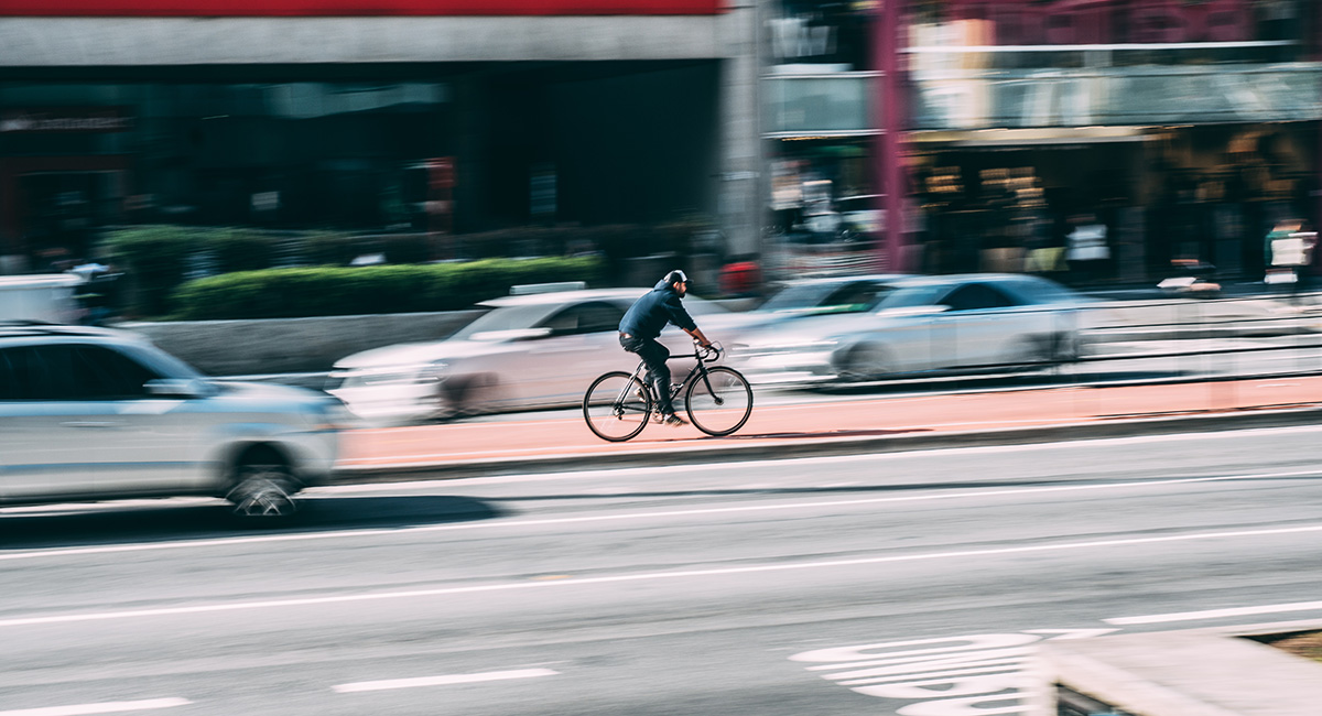 Ein Radfahrer fährt auf einem in Rot markierten Radweg im Stadtverkehr zwischen Autos.