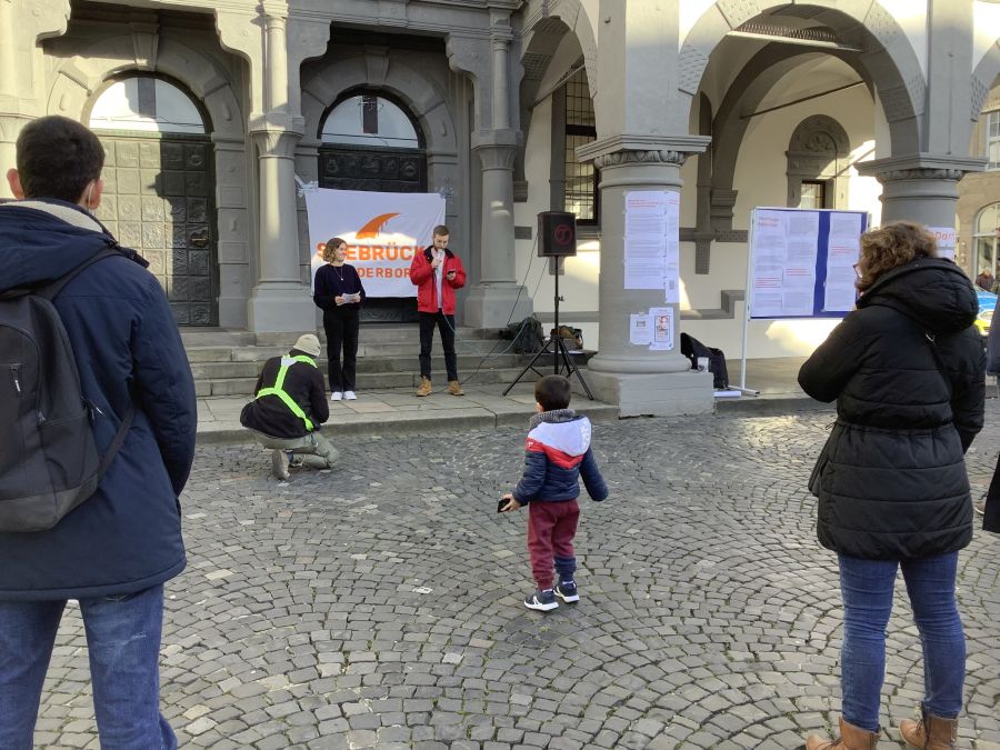 vor dem paderborner rathaus sprechen seebrücken-mitglieder, menschen hören zu