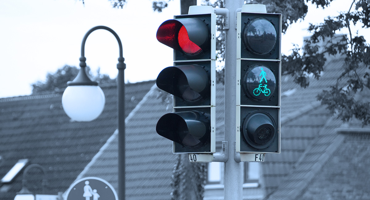 Eine Ampel zeigt Rot für den KFZ-Verkehr und Grün für Fußgänger und Radfahrer.