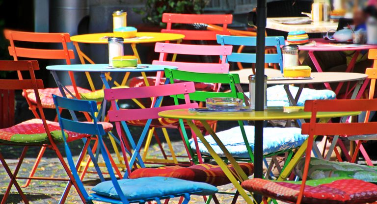 Ein Biergarten mit vielen bunten Stühlen und Tischen.