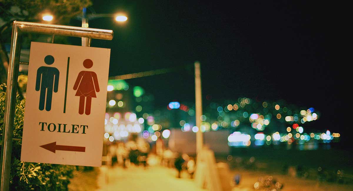 Ein Toiletten-Hinweisschild auf einem beleuchteten Festplatz in der Nacht.