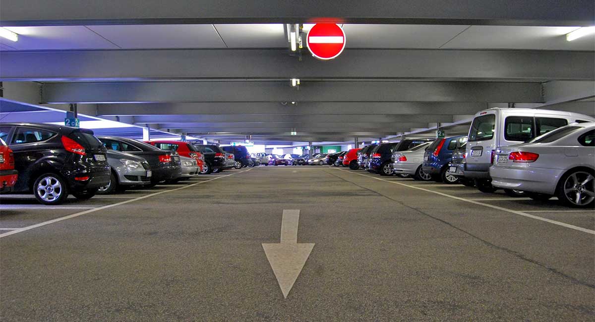 Parkdeck eines Parkhauses mit einer Zufahrt in der Mitte und vielen rechts und links davon parkenden KFZ.