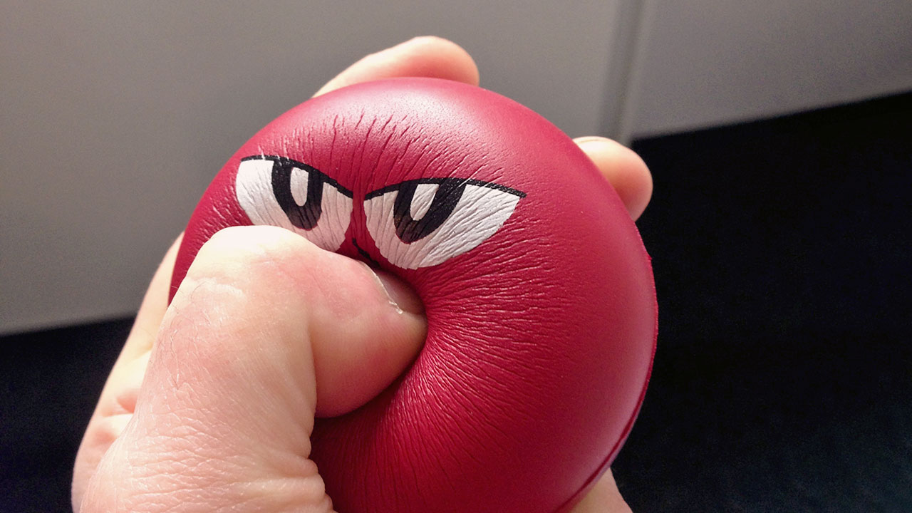 Ein roter Stressball wird geknetet.