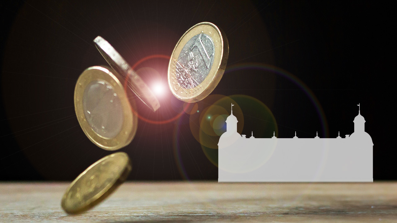 Euromünzen fliegen vor der Silhouette von Schloß Neuhaus durch die Luft.
