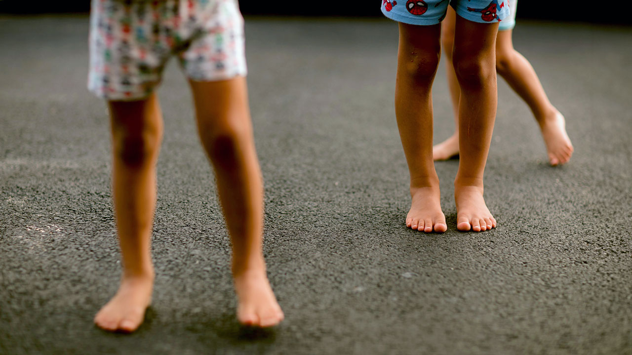 Kinder spielen barfuß auf einer Straße.