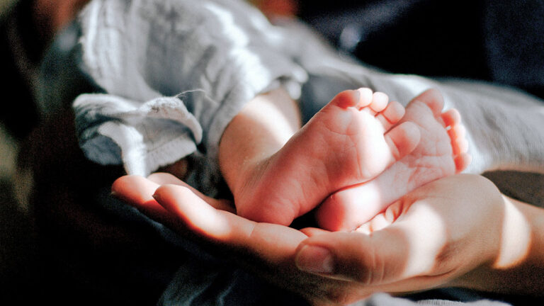 Eine Hand hält die Füße eines Babys.