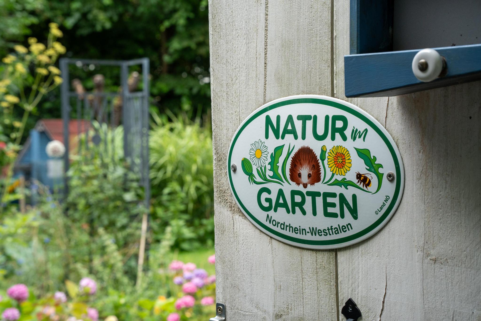 Bild mit einem Blick in einen Garten und ein Schild "Natur im Garten"