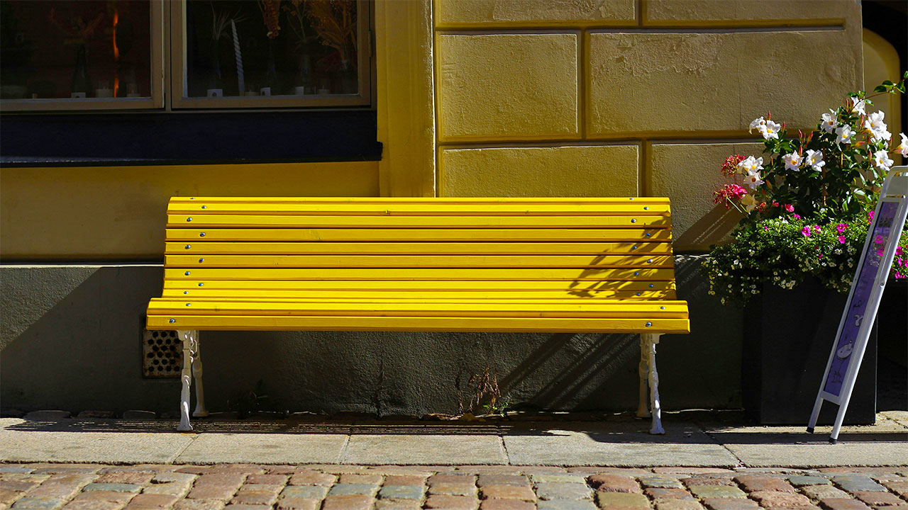 Eine gelbe Sitzbank vor einem Gebäude.